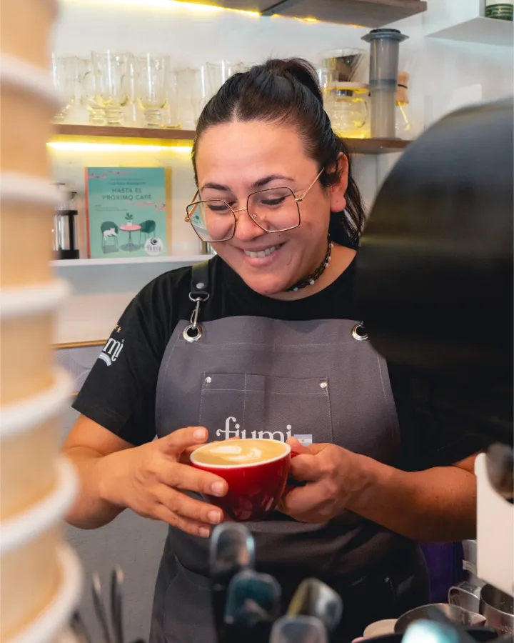 Una barista de Fiumi sonriendo con una taza en las manos