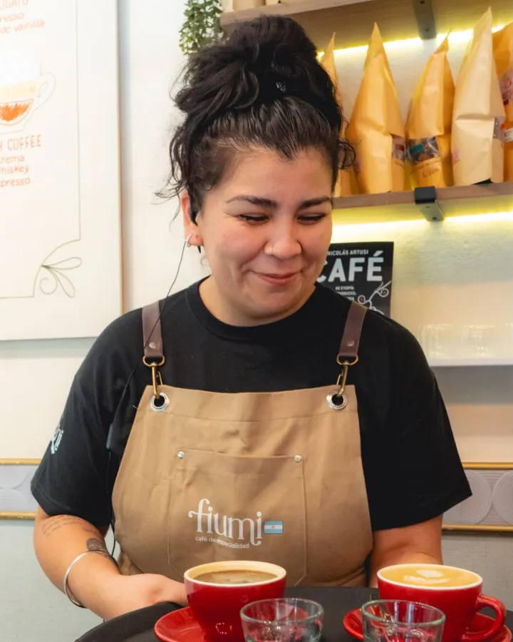 Una barista de Fiumi sonriendo con dos cafés recién servidos