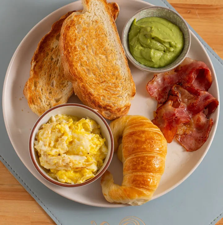 Plato del Desayuno Fiumi con tostadas, huevos revueltos, panceta, palta y medialuna