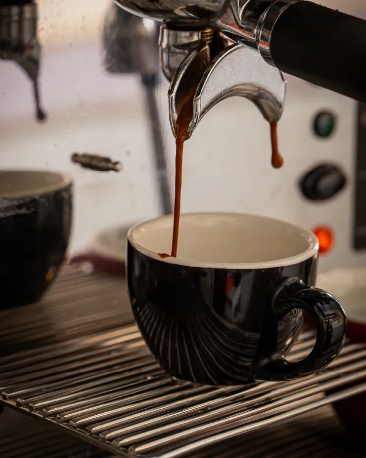 Espresso cayendo de la máquina en una taza negra