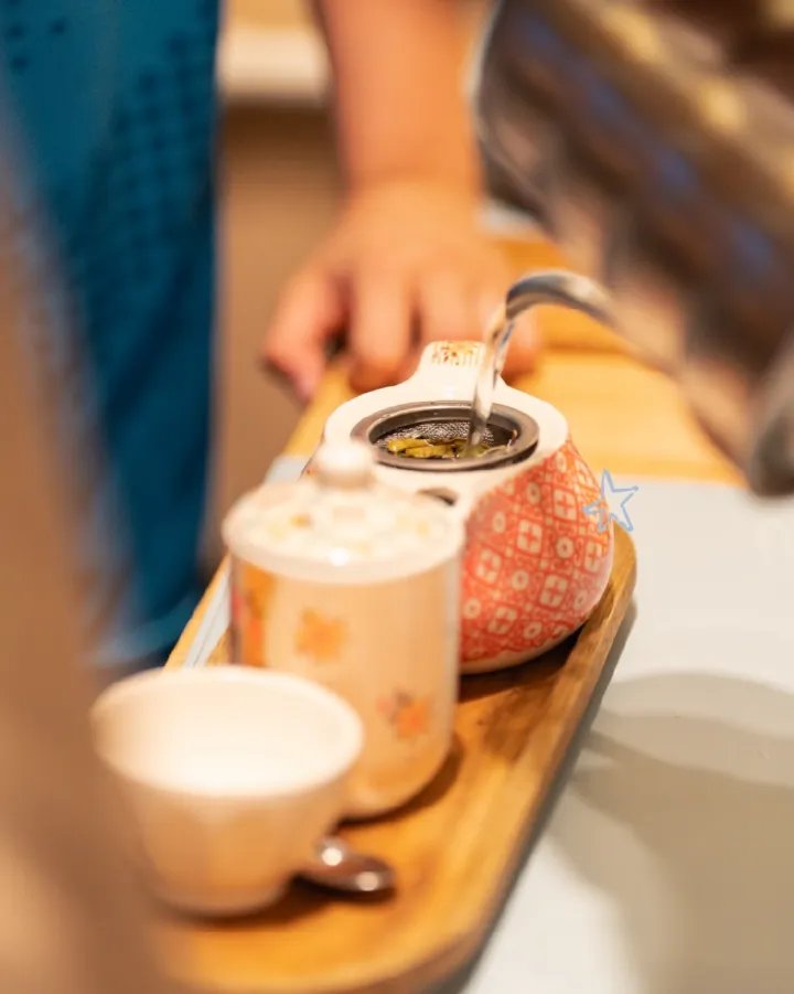 Tetera con té en hebras, taza y azucarera sobre bandeja de madera